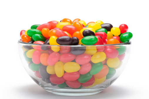 Colorful sugar coated chocolate candies in wooden bowl on white background with space for text, selective focus, top view.