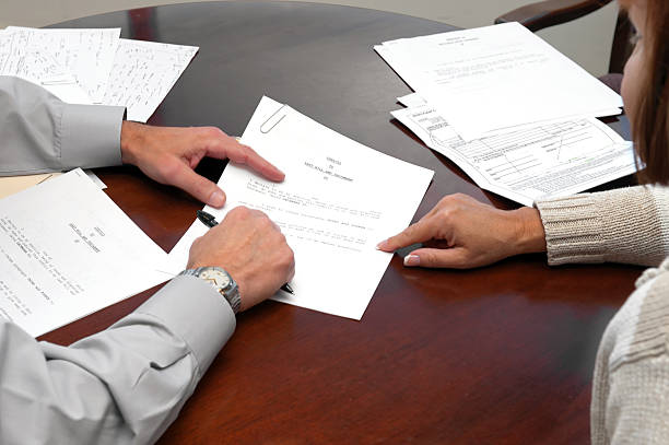 A woman making a formal business agreement signing a will codicil to a last will and testament and irrevocable trust being signed by a 50 year old woman.  jodijacobson stock pictures, royalty-free photos & images