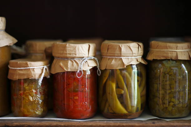 Row of canned vegetables in 19th century style canning jars with paper tops