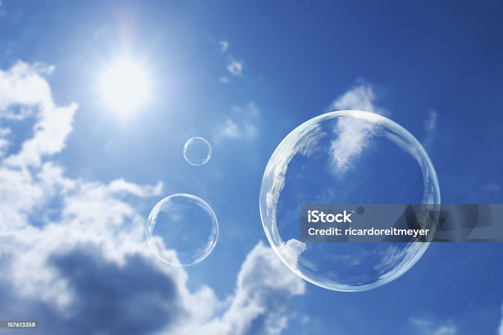 Floating Soap Bubbles Against Clear Sunlit Blue Sky and Clouds These soap bubbles float calmly against a clear deep blue sky and clouds representing natural 'Thought Bubbles' on possible ideas for clean atmosphere, fresh air and a green environment. Soap Sud Stock Photo