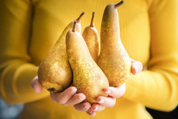 Close up of green pear in hand on white background