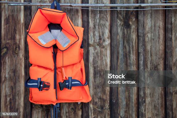 Chaqueta De Vida Para Un Niño En Contra De Una Vieja Pared De Madera Foto de stock y más banco de imágenes de Chaleco salvavidas