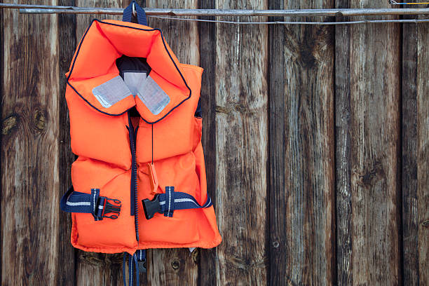 gilet de sauvetage pour un enfant contre un vieux mur en bois. - life jacket photos photos et images de collection
