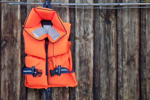 Life jacket for a child against an old wooden wall.