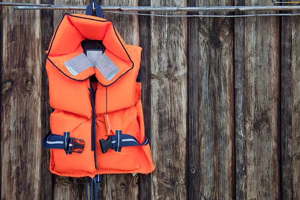 Life jacket for a child against an old wooden wall.