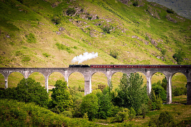 Antique Steam Train running on a Viaduct Old locomotive running on the roman Glenfinnan Viaduct on River Finnan in Scotland. fort william stock pictures, royalty-free photos & images