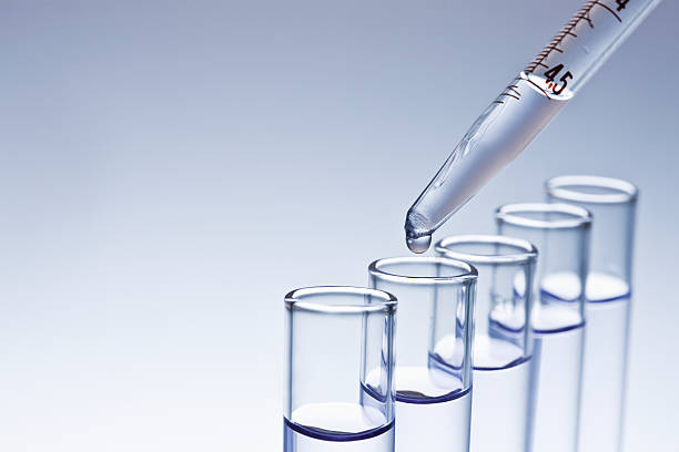 Dropper Filling Test Tubes Medicine dropper with a clear liquid is filling test tubes. Horizontal shot. medicine and science drop close up studio shot stock pictures, royalty-free photos & images