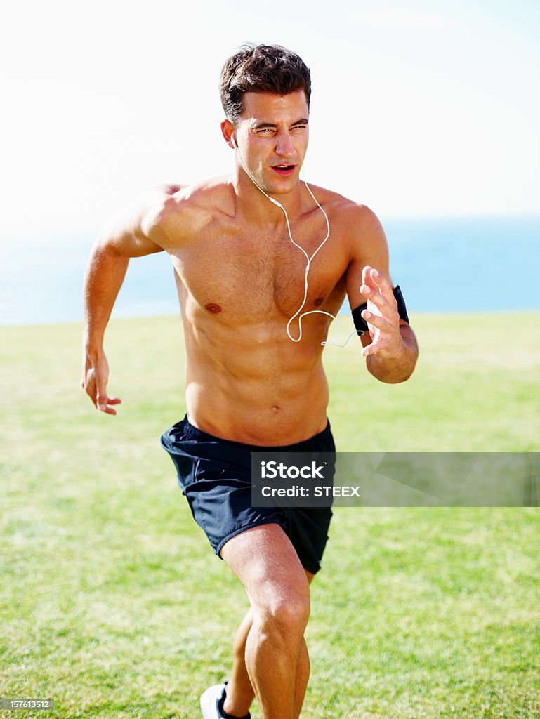 Mężczyzna sportowiec joggingu podczas słuchania muzyki - Zbiór zdjęć royalty-free (25-29 lat)