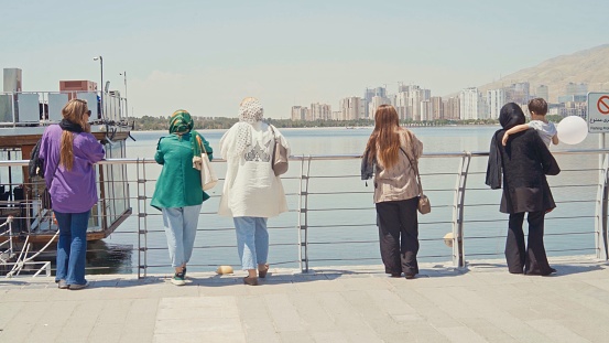 Iranian Women with and without Hijab standing and observing next to Chitgar Lake an artificial lake in Tehran, Iran