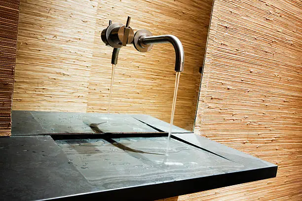 Photo of Handwashing water runs onto slate slab in ultramodern bathroom