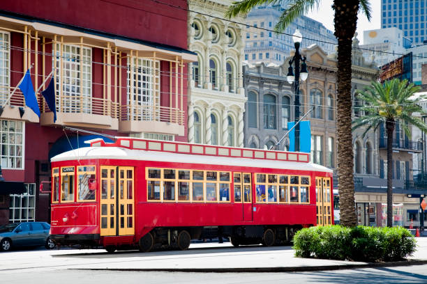 new orleans straßenbahn rot auf reisen, umgeben von palmen und flaggen - cable car fotos stock-fotos und bilder