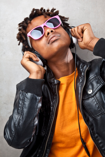 Portrait of african teenager with sunglasses listening music with headphones.
