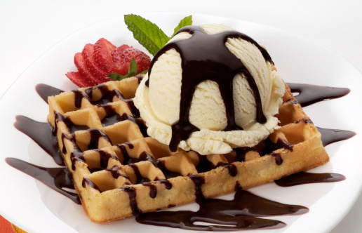 Vanilla ice cream with chocolate sauce on a waffle,decorated with strawberry and mint.