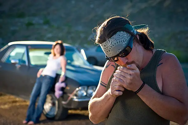 Photo of whiskey tango Redneck lights cigarette before girlfriend and car