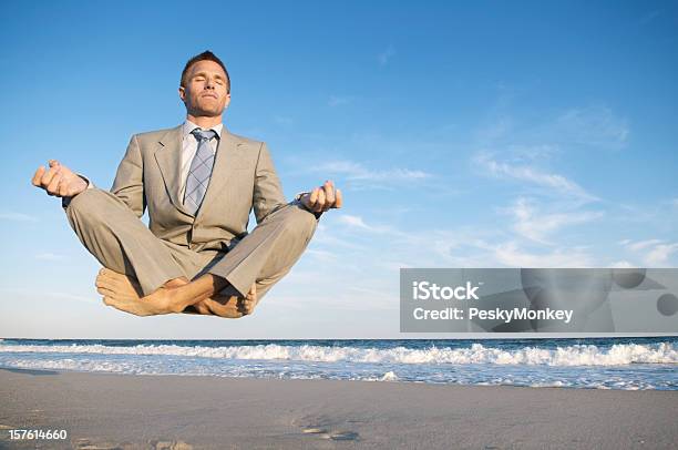 Peaceful Meditating Businessman Levitating Above Tranquil Beach Stock Photo - Download Image Now