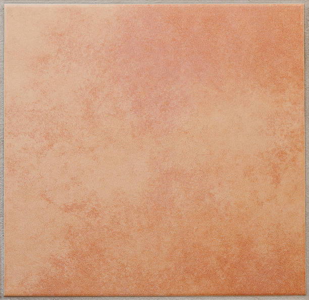 Single apricot colored ceramic tile textured full frame Cloudy, mottled patterned square floor tile, terracotta, surrounded by a grey tile joint or grouting. Red and sandy colored. Italian style. Square orientation. The image has been shot full frame and close up. Ideal for backgrounds. The size of the photo is 2000 x 1943 px. terracotta stock pictures, royalty-free photos & images