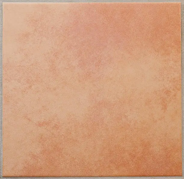 Photo of Single apricot colored ceramic tile textured full frame