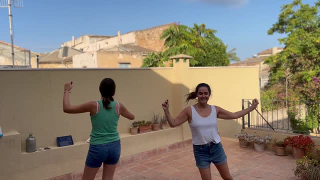 Two girls taking online dance class in the backyard