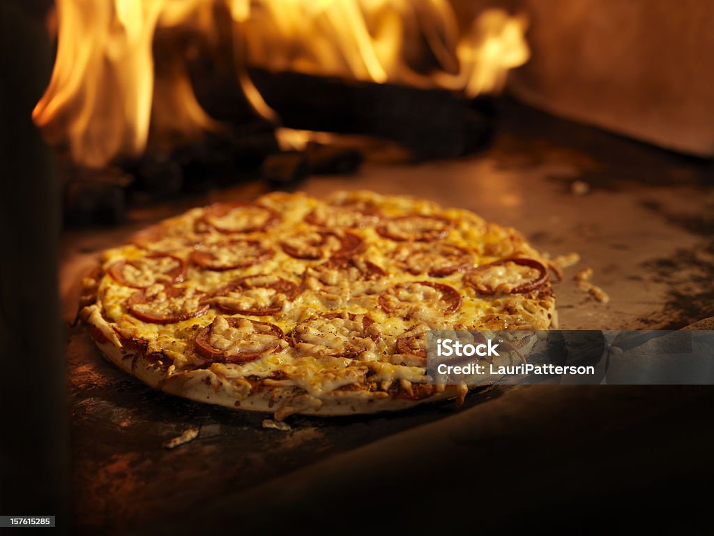 Pizza alla salsiccia piccante in un forno a legna - Foto stock royalty-free di Pizza