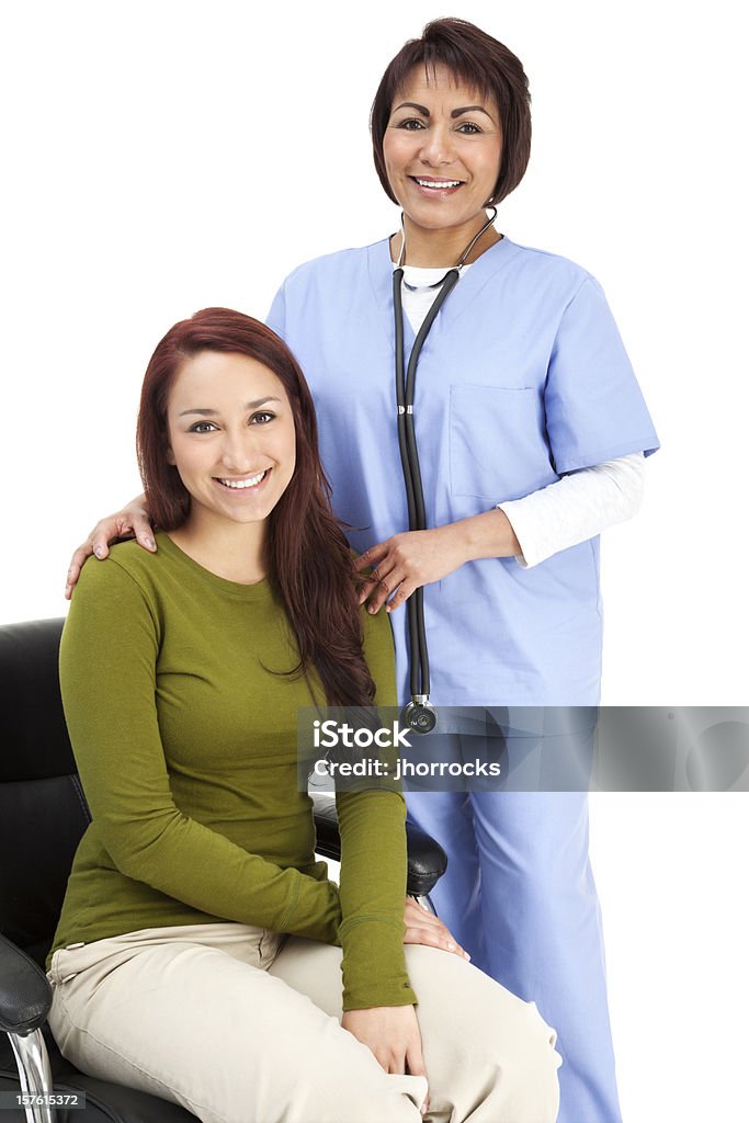 Hispanic enfermera en azul exfoliaciones con jóvenes paciente - Foto de stock de Enfermera libre de derechos