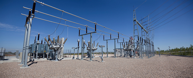 High voltage transformer with electrical insulation and electrical equipment at a power substation. The three-phase radiator-cooled transformer is equipped with a forced air cooling fan.
