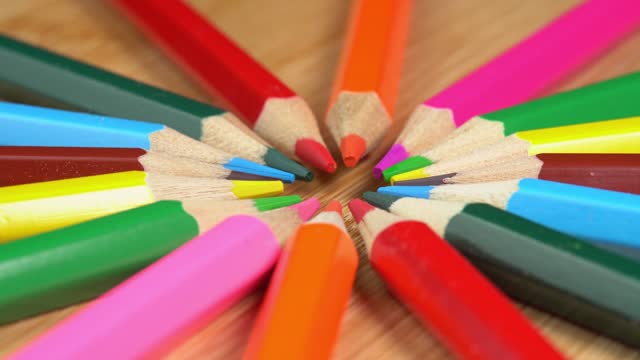 Colorful pencils rotate as sun rays background. Rainbow pencils for drawing. Assortment of colored pencils. Back to school concept
