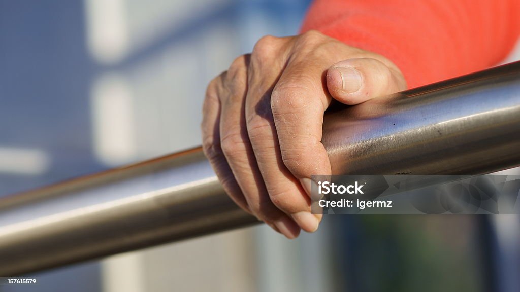 Senior Hand Grasps Stainless Steel Railing Low angle view of an unrecognizable, senior adult, woman grasping a stainless steel safety rail with her right hand. Railing Stock Photo