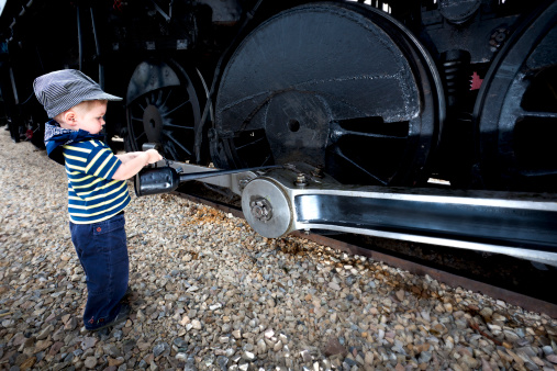 Young Boy plays mechanic on a Old Steam Train. Antique Oil Can Used.
