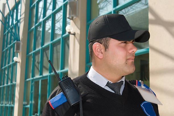 Security guard wearing a ball cap in front of a building stock photo