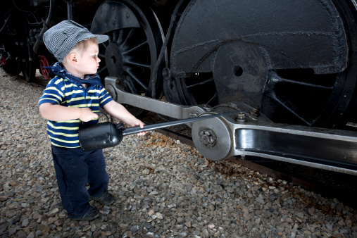 A young boy plays mechanic with an Antique Oil can, all dressed up for the part.
