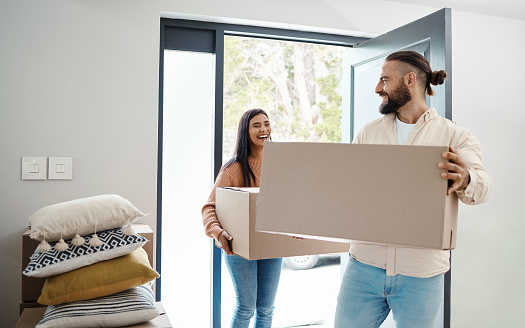 Couple moving, new house and box with happiness, man and woman, real estate property and home owner. Mortgage, laughing and walk in front door, partnership and happy with relationship and relocation