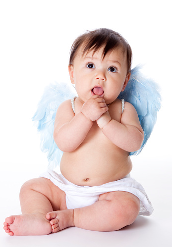 6 month old baby sitting wearing blue wings, looking like an angel, on white background