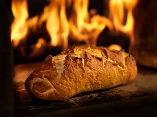 Warm, crusty loaves of wheat bread are neatly arranged in a woven basket, showcasing their golden crust and soft interior on a sunny morning.