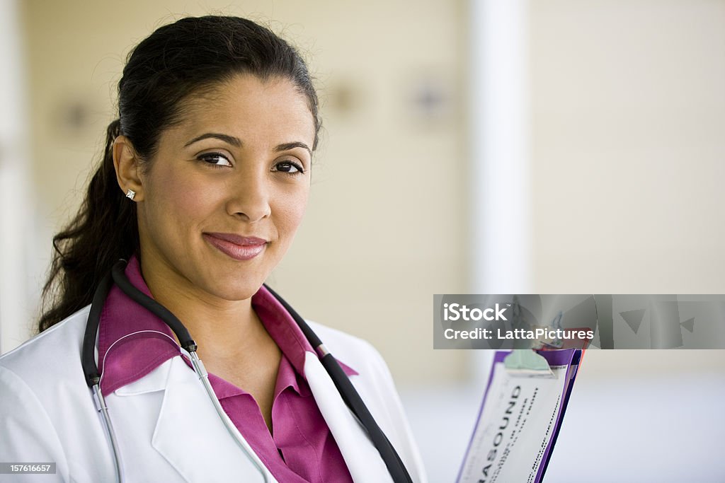 Médico feminino segurando a prancheta e sorrindo - Foto de stock de Doutor royalty-free