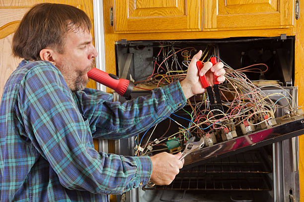 Humorous Major Appliance Repair Comical repairman humorously fixes a household over in a home kitchen using a flashlight in mouth,and wire cutters in one hand, and wrench in another hand  door panel stock pictures, royalty-free photos & images