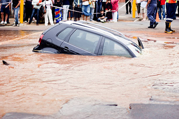 Car slips under muddy water in flooded street  sinkhole stock pictures, royalty-free photos & images
