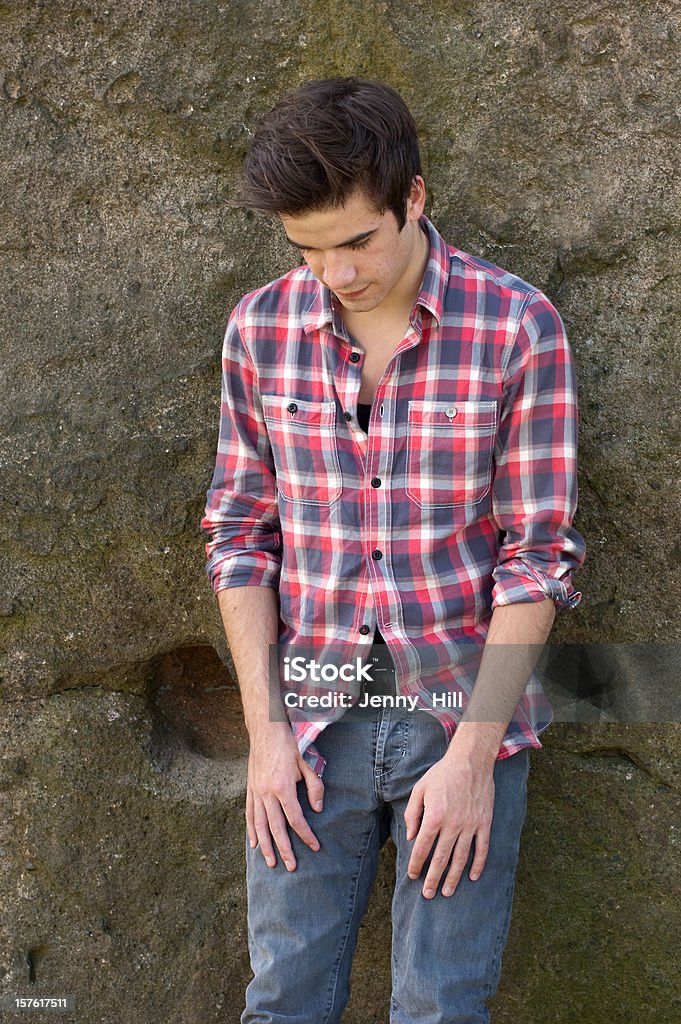 Atraente jovem encostando contra uma parede de rocha - Foto de stock de 16-17 Anos royalty-free
