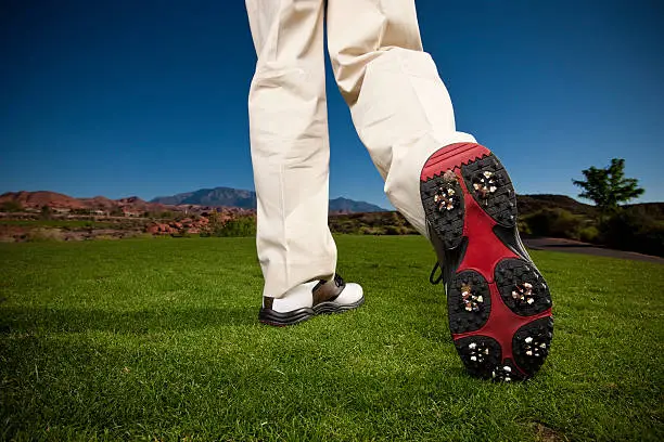 Low angle close-up of the bottom of a golfer's modern, new golf shoe on the green right after the swing.