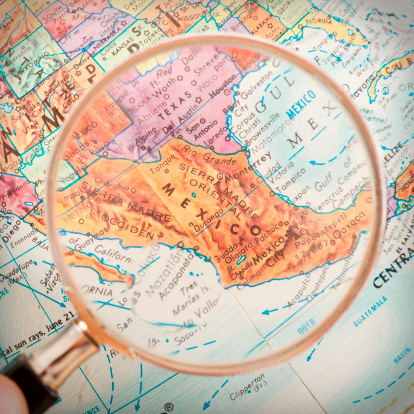 Studying Geography - Photograph of Mexico on retro globe underneath a magnifying glass. 