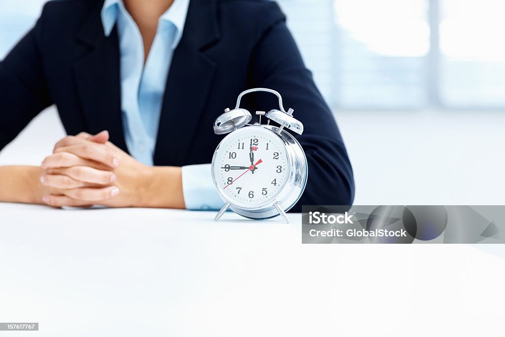 Mid section of a business woman with alarm clock  Business Stock Photo