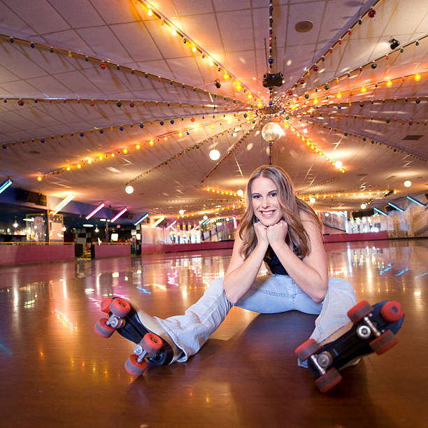 Retro Roller Skating. A young woman sits and smiles on the floor of a retro roller skating rink from the 1950s, 1960s era.  Click to view similar images. roller rink stock pictures, royalty-free photos & images