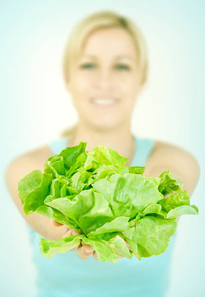 Young happy woman holding fresh green salad as symbol of healthy food.