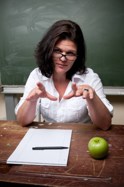 istock Female teacher sitting in classroom, gesturing 157618122