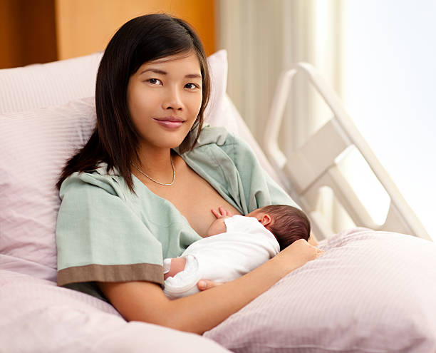 Woman in a hospital bed breastfeeding a child stock photo
