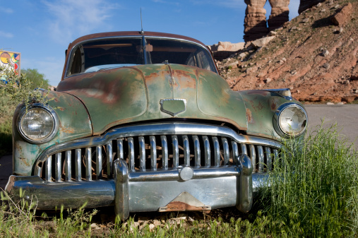 A rusty 1949 Buick Super Sedanette sits in a field, slowly decomposing in the arid desert climate of Utah.  Its headlight is broken, the tires are flat, but the sleek lines of this roadster are still evident.