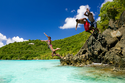 four teenagers jumping into the water in the Caribbean