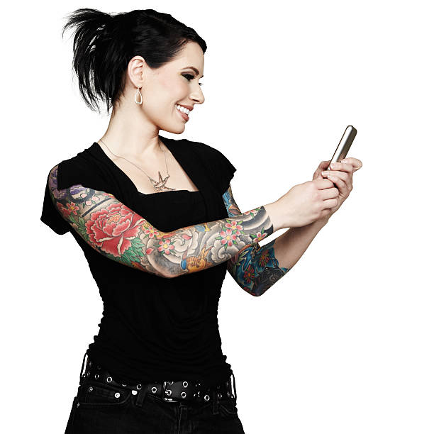 Beautiful tattooed woman smiles while using mobile phone. White background. stock photo