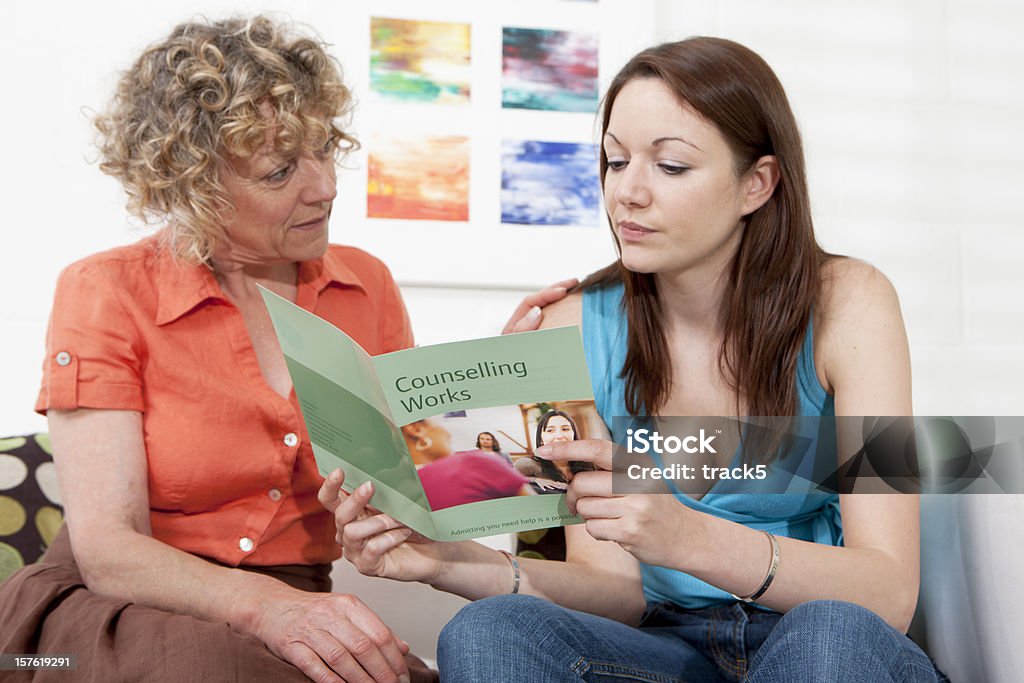 Dos mujeres mirando a un'counselling works'folleto - Foto de stock de Folleto libre de derechos