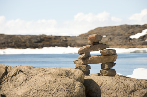 An inukshuk marker stands beside a river that flows into Frobisher Bay on Baffin Island.  Click to view similar images.