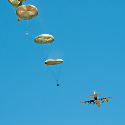 Air drop of four pallets from C-130 airplane during a military training exercise.